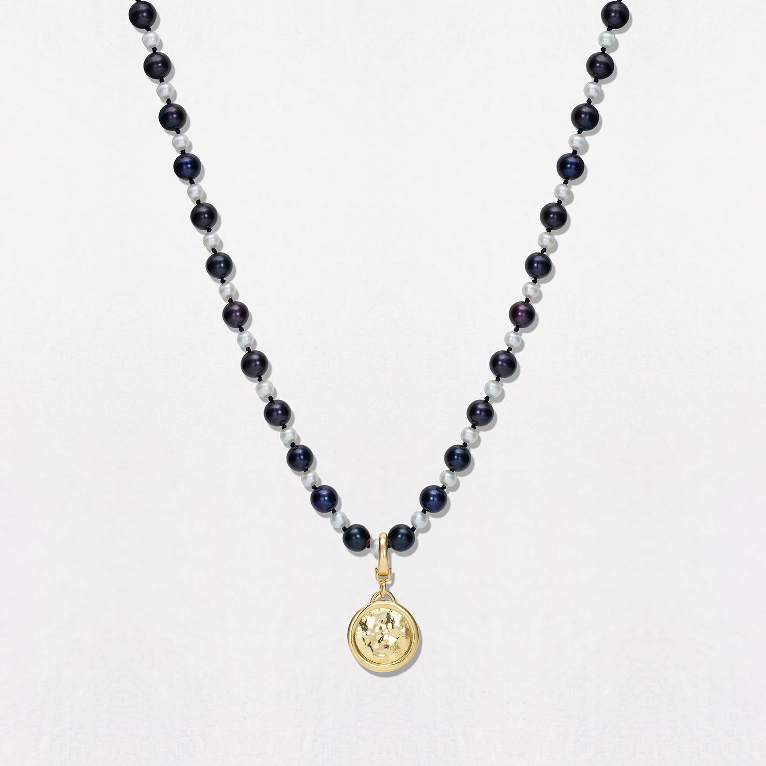 A Small Pearl Knot Necklace with a set of white & black freshwater pearls, 4-5mm in diameter, strung and knotted on navy thread, with an 18K yellow gold clasp. Total necklace length is 15". Custom-made sizes available on request.