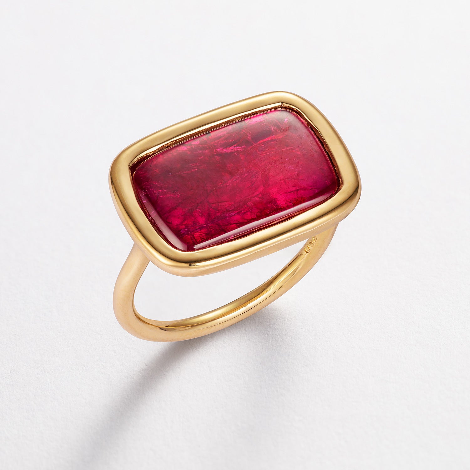 Bespoke 18k gold ring with a red ruby slice on a light gray background by Isabella Roux
