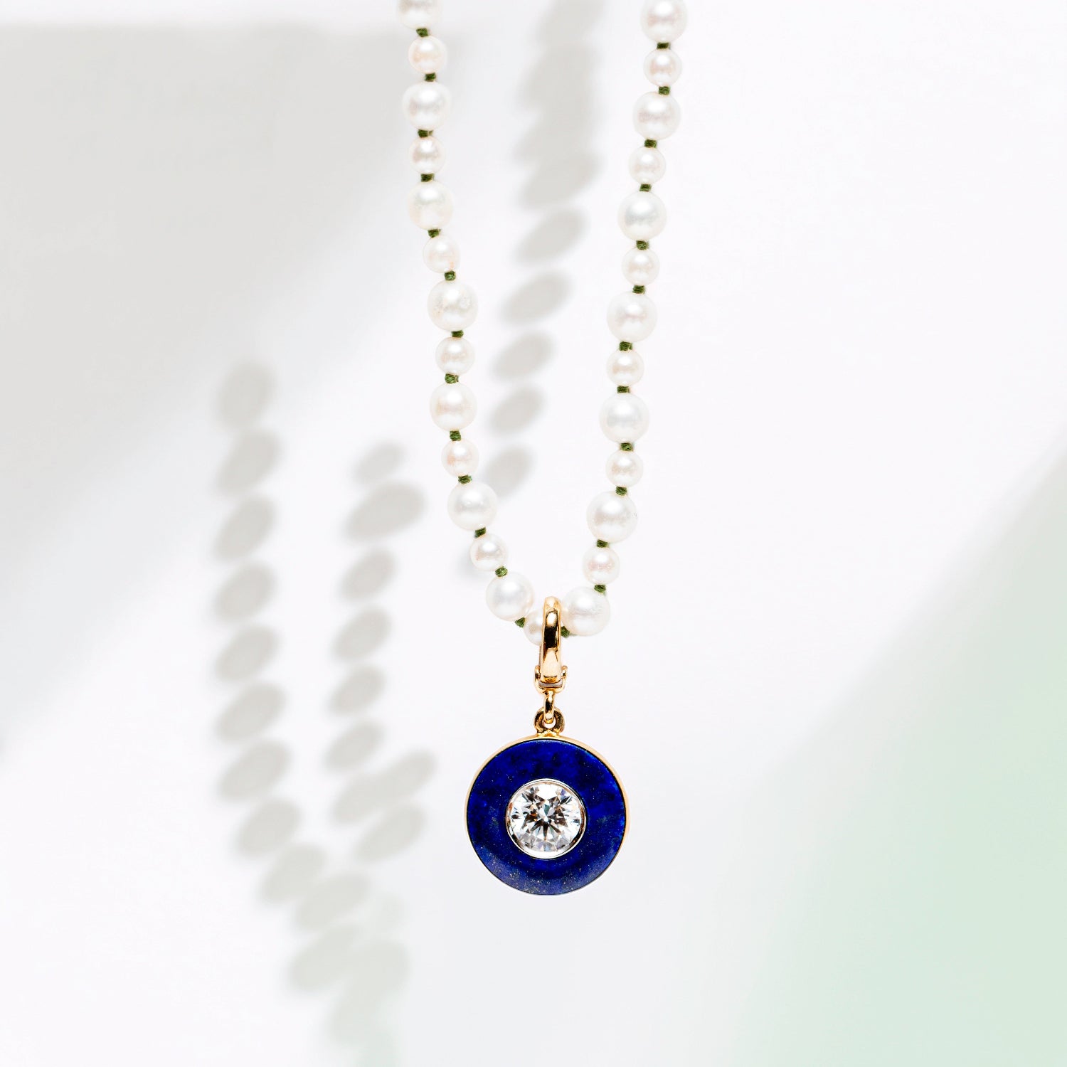 Handcrafted 18K yellow gold Diamond Lapis Pendant featuring a 1.55ct round brilliant lab grown diamond surrounded by a deep blue lapis lazuli inlay with a detachable clasp on a pearl necklace by Isabella Roux.