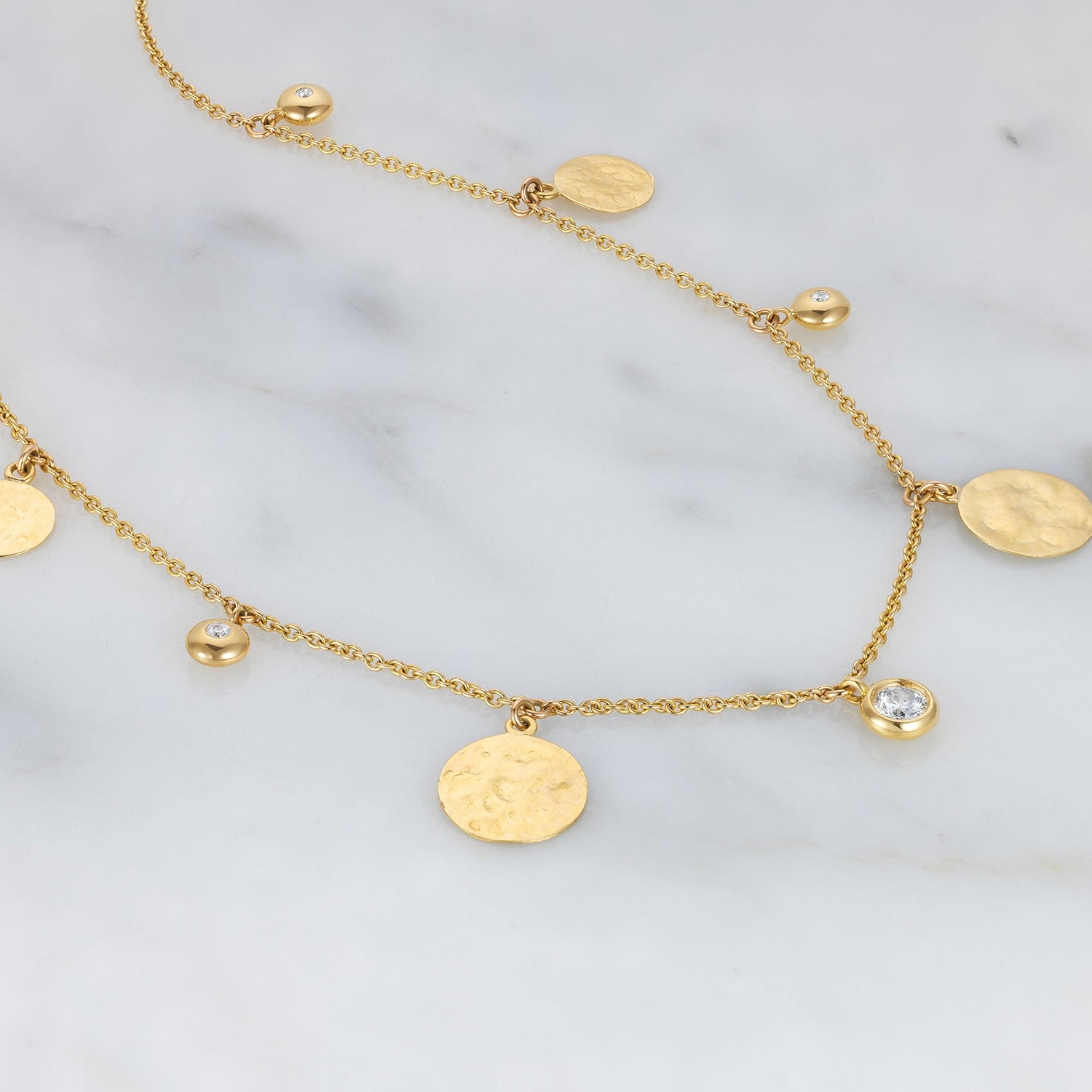 Handcrafted 18K yellow gold Diamond Pebbles & Sun Disk Necklace featuring a mix of beaten sun discs and 0.5 ct diamonds in pebble settings by Isabella Roux