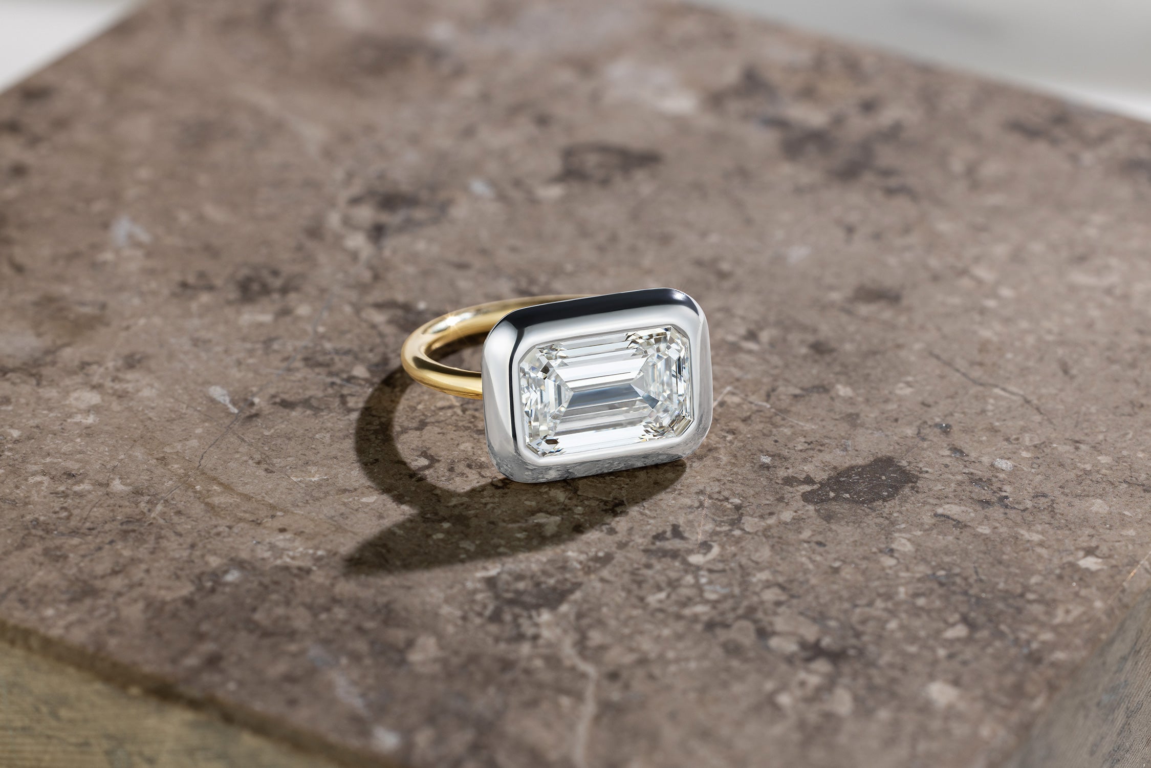 Handcrafted 18K yellow and white gold Emerald Cut Diamond Cup Ring featuring a 3.95ct emerald cut lab grown white diamond set in a bezel style cup by Isabella Roux