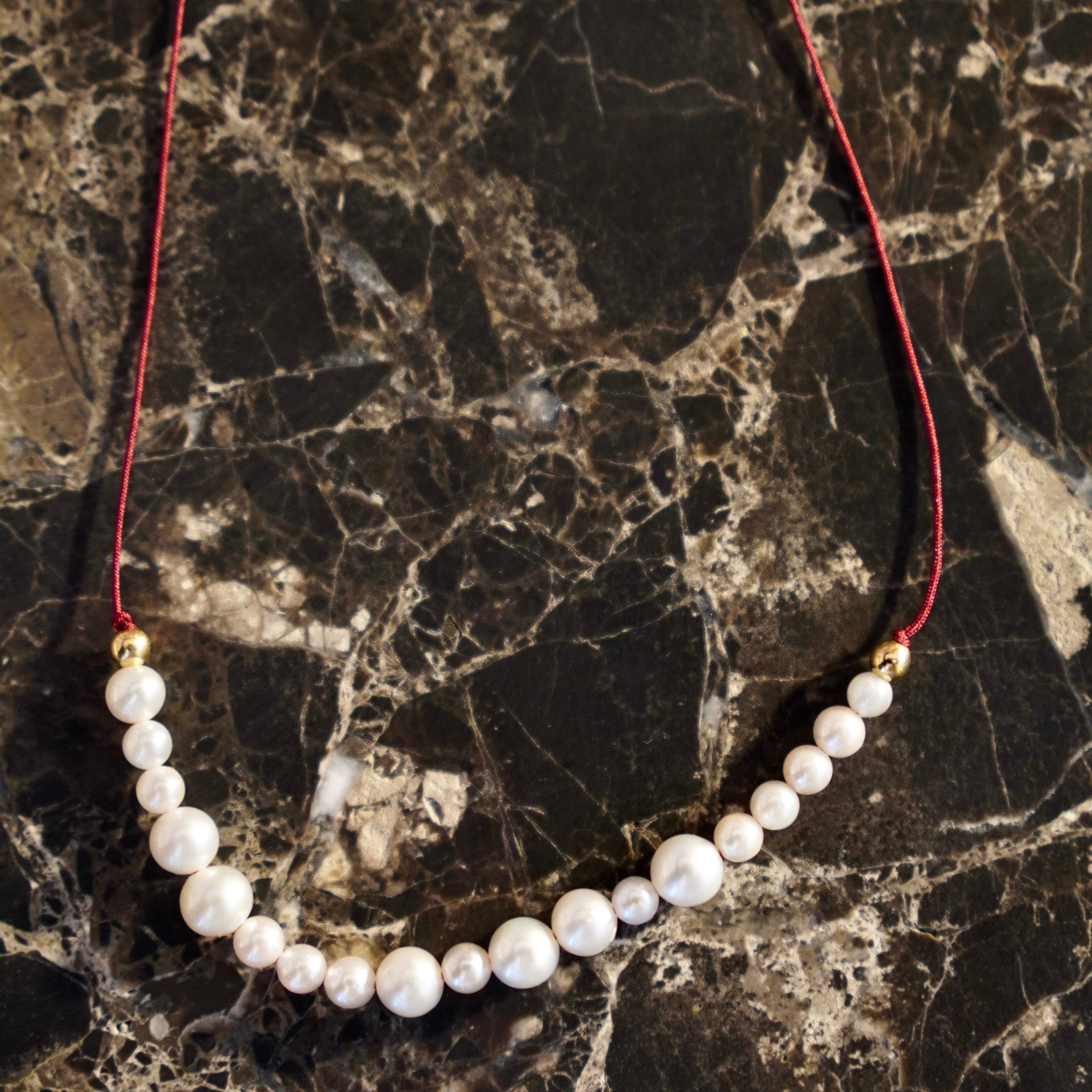 Handcrafted Pearl Cord Necklace featuring a mix of 3-6mm white freshwater pearls on a burgundy red cord with 18K yellow gold fittings by Isabella Roux