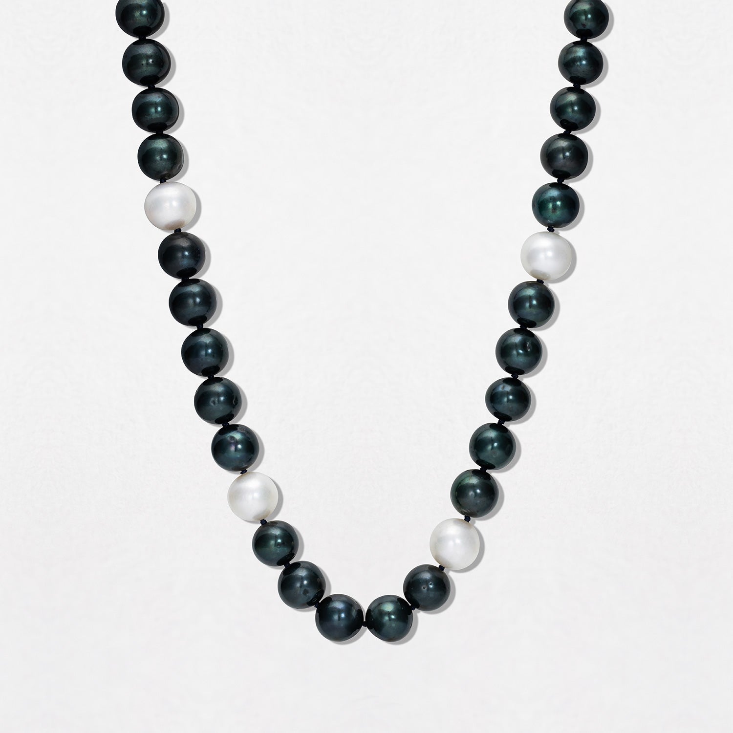 Handcrafted Pebble Black & White Pearl Necklace featuring 9-10mm black and white freshwater pearls knotted on navy thread with an 18K yellow gold clasp by Isabella Roux