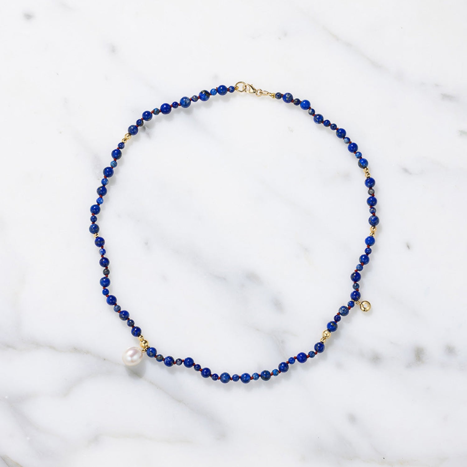 Handcrafted 18K yellow gold Pebble Lapis & Pearl Necklace featuring deep blue lapis lazuli, freshwater pearl drop, strung on red thread by Isabella Roux