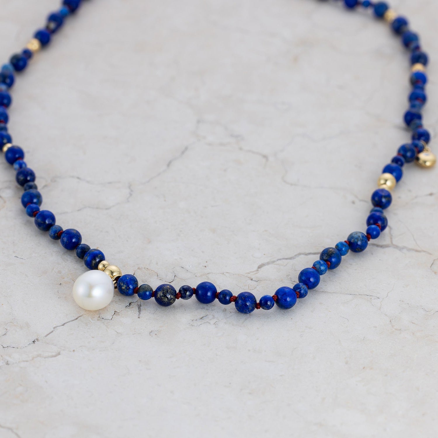 Handcrafted 18K yellow gold Pebble Lapis & Pearl Necklace featuring deep blue lapis lazuli, freshwater pearl drop, strung on red thread by Isabella Roux