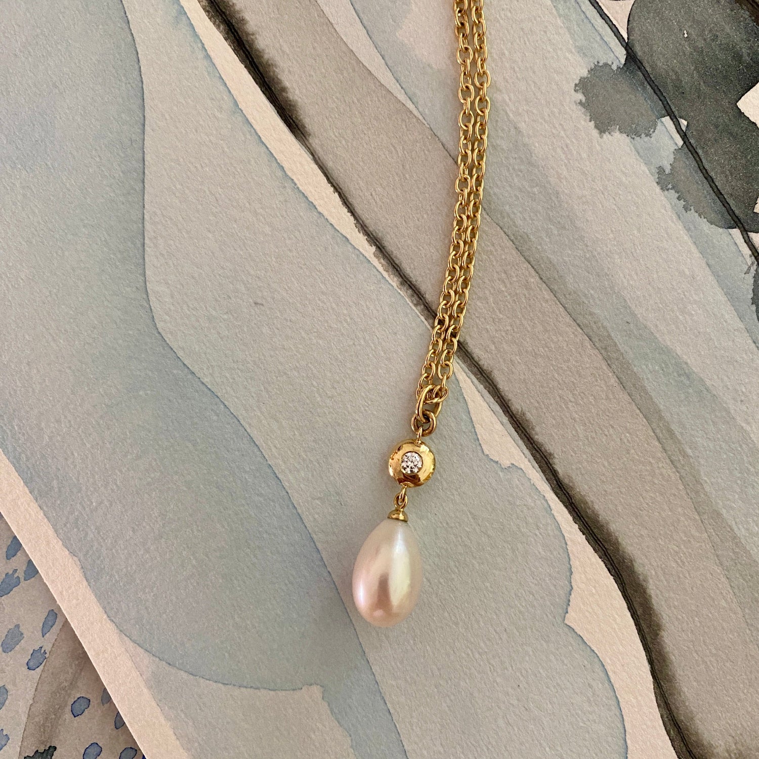 Handcrafted 18K yellow gold Pebble Pearl & Diamond Pendant featuring a 0.10ct round brilliant-cut lab diamond bezel-set in a signature gold pebble shape with a white Akoya pearl drop on a 22" chain by Isabella Roux.