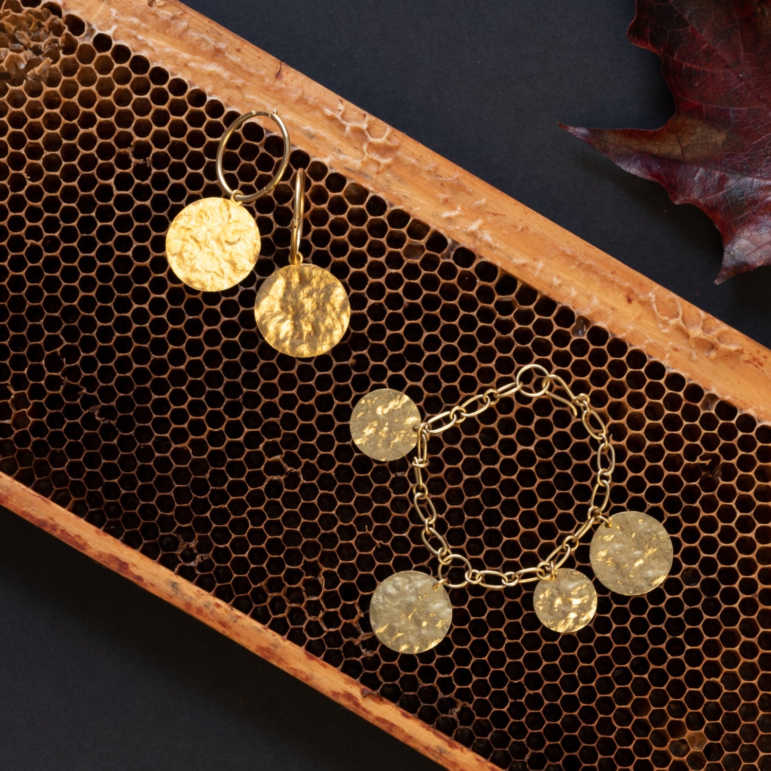 Still life with handcrafted 18K yellow gold Sun Disc Large Hoop Earrings featuring 25mm hoops with detachable 25mm hand-beaten gold discs by Isabella Roux.