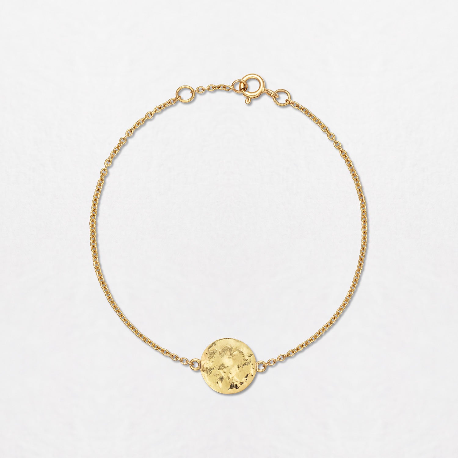A Sun Disc Bracelet, handbeaten in 18K yellow gold, on a gold chain. The diameter of the disc is 11mm. Total bracelet length is 6.5".