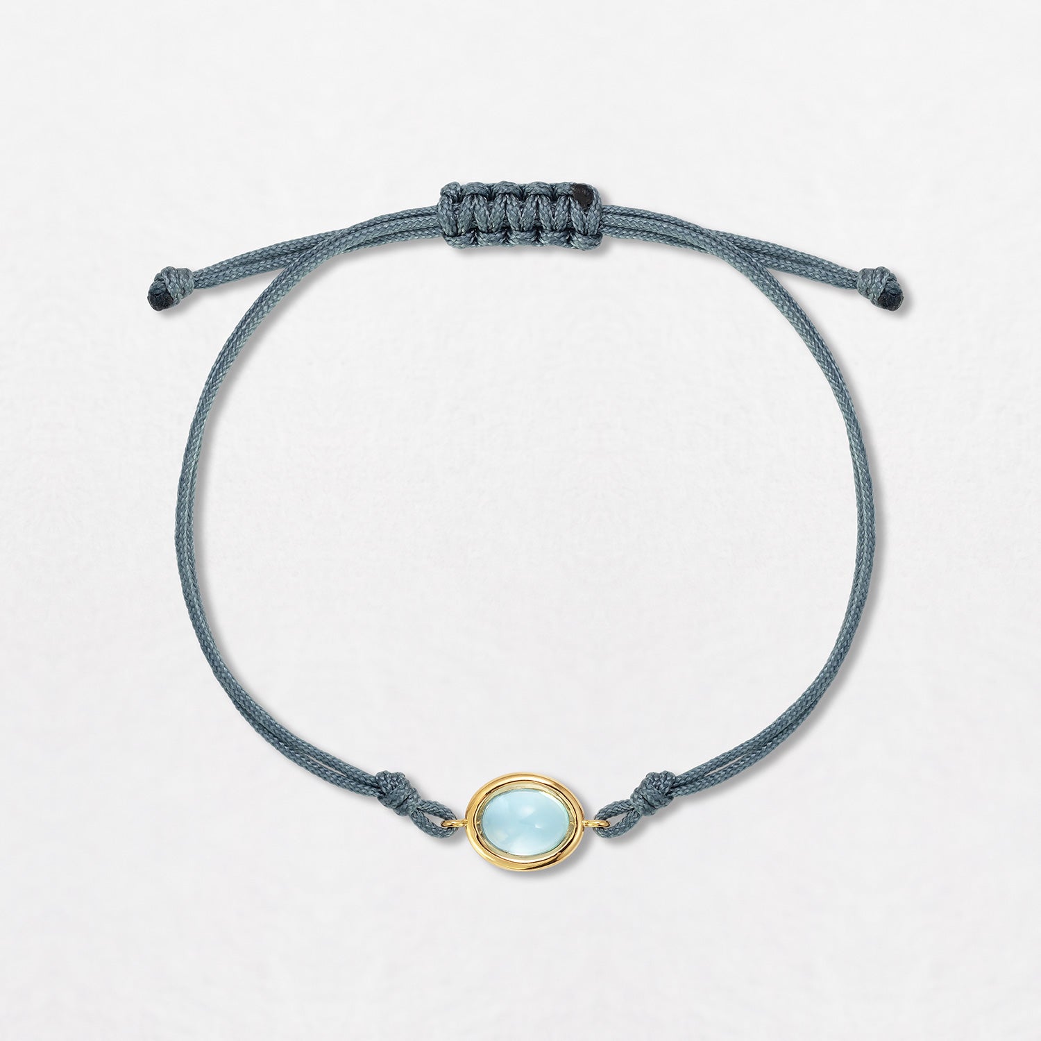 A Swiss Blue Topaz Pebble Bracelet with a 2ct light topaz cabochon. Set in 18K yellow gold double grey cord, with an adjustable slider fastening.