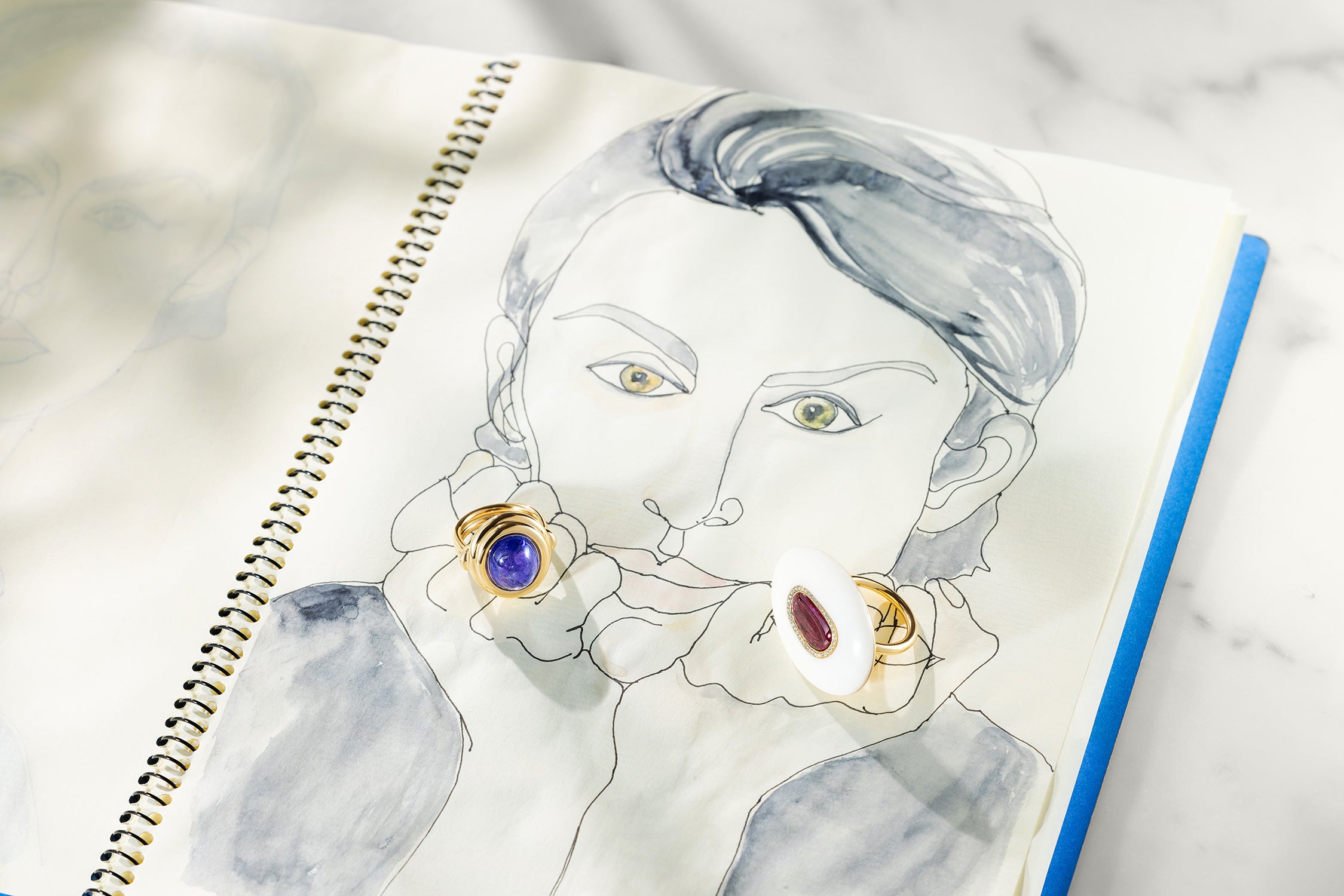 Artistic jewellery illustration of a woman's face with bespoke 18k gold rings on a notebook by Isabella Roux