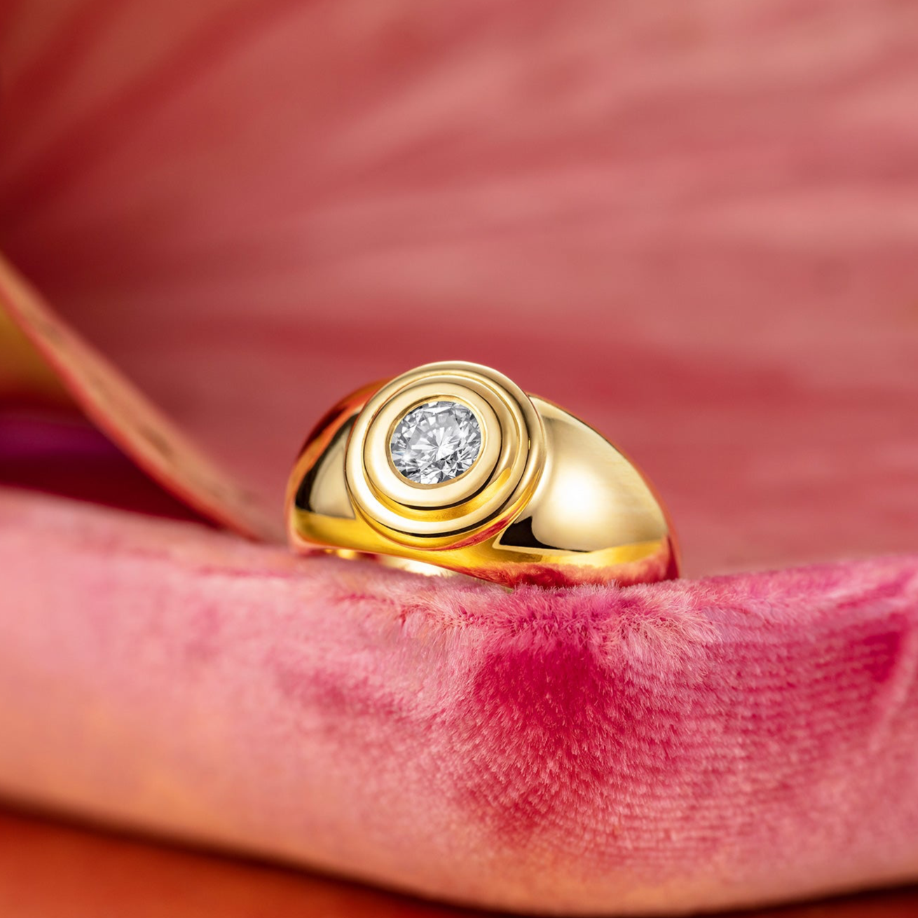 Bespoke 18k gold ring with a diamond on a pink fabric background by Isabella Roux