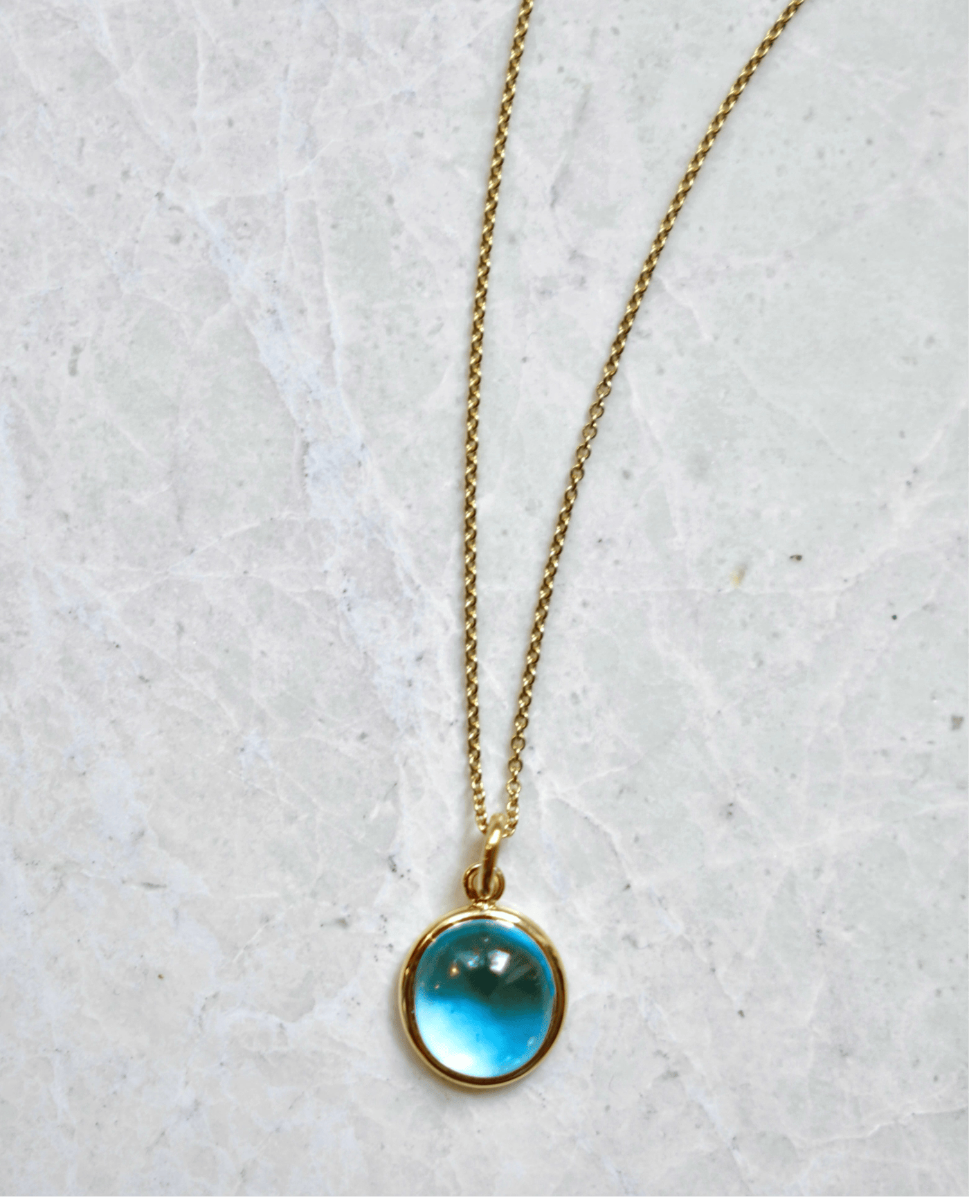 Bespoke 18k gold necklace with a pendant on a light gray background by Isabella Roux