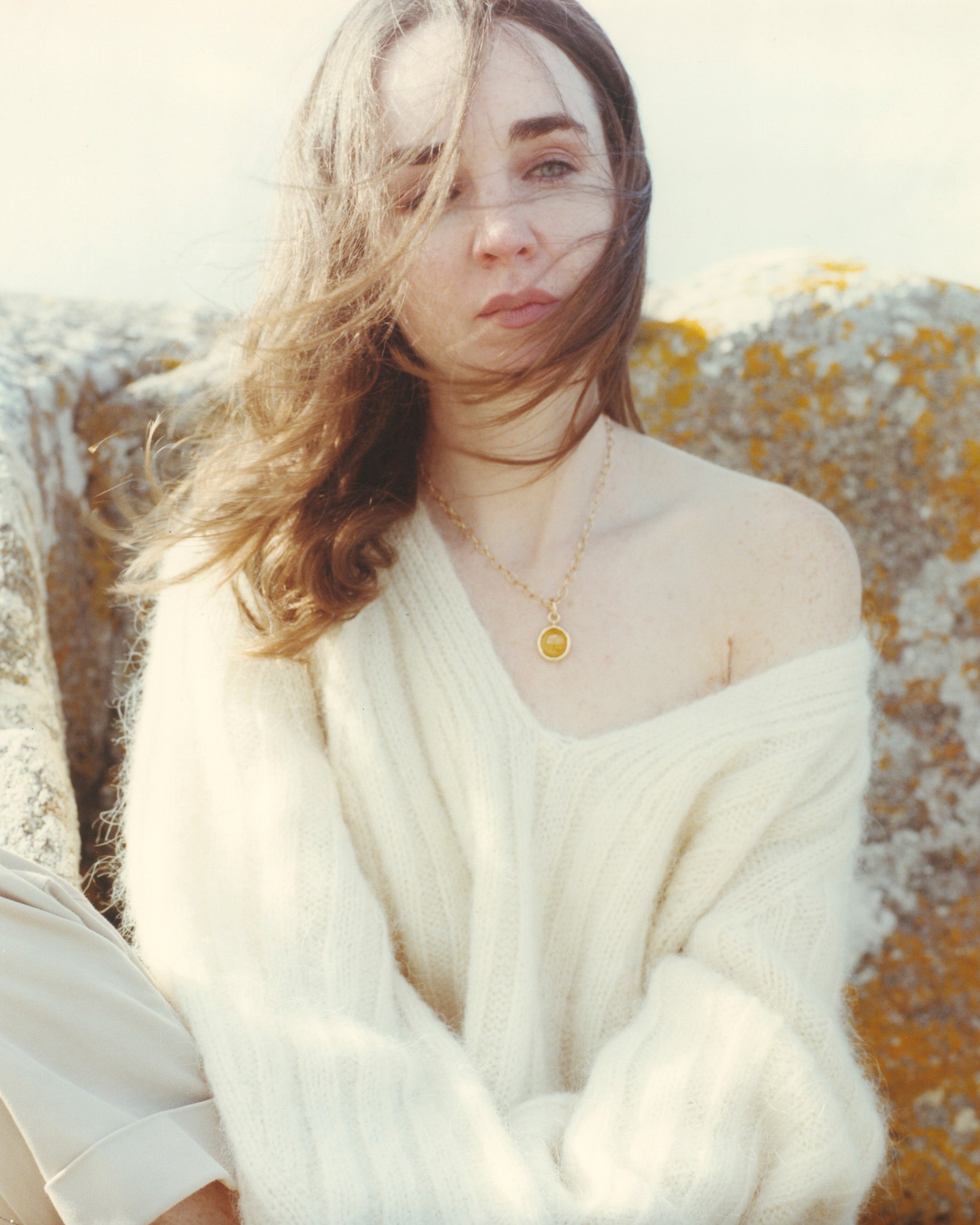 Isabella Roux lookbook image wearing a white sweater with a blurred natural background