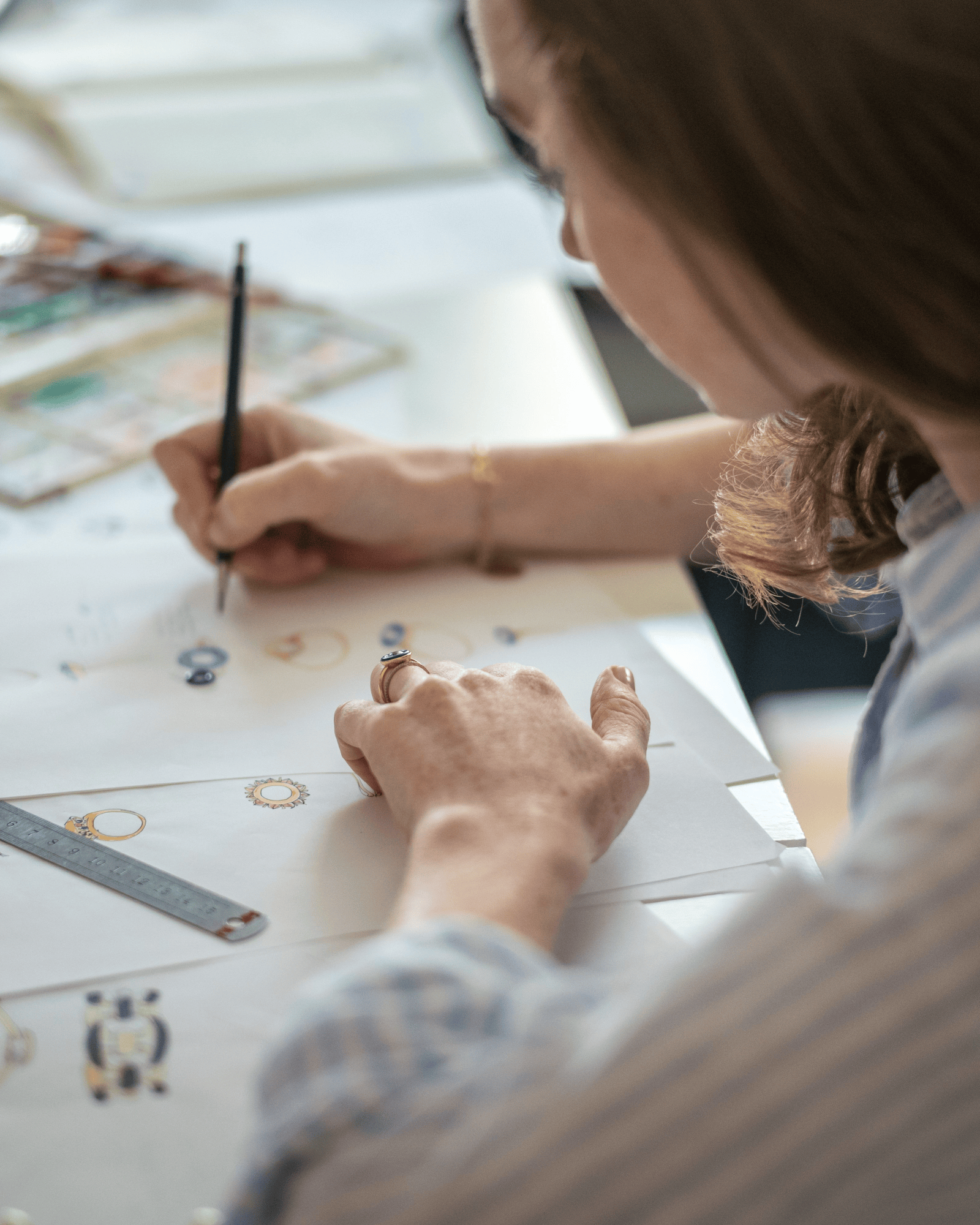 Isabella Roux drawing on a piece of paper with a pencil, surrounded by art supplies.