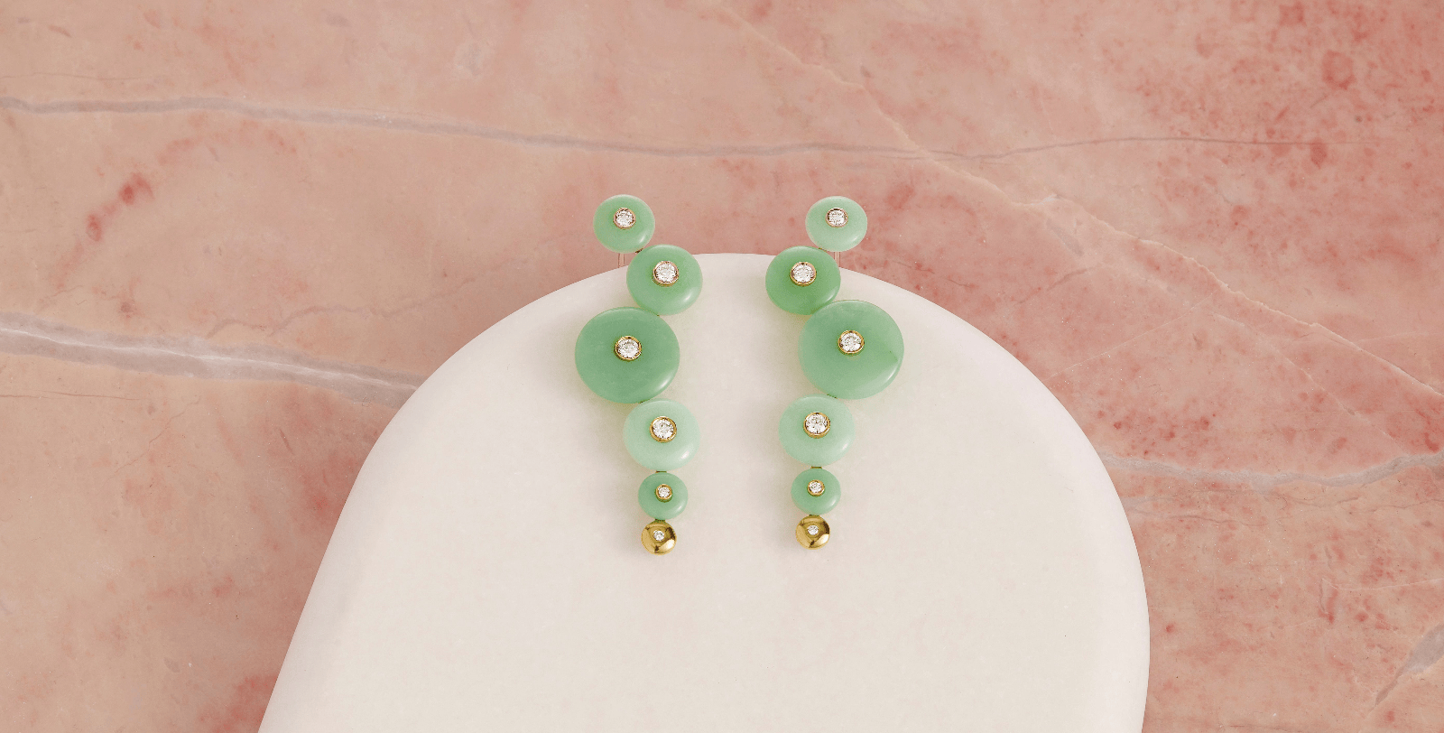 Green Chrysoprase earrings on a white stand with a pink background