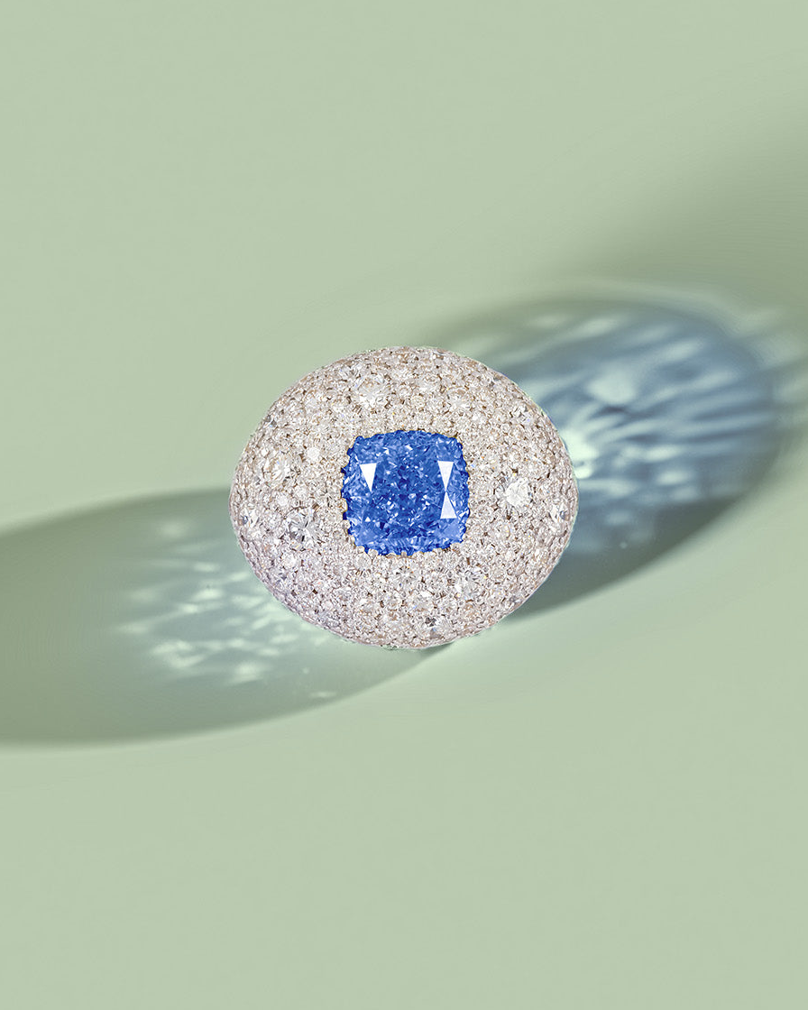 18k gold bespoke diamond ring with a blue gemstone on a light green background by Isabella Roux