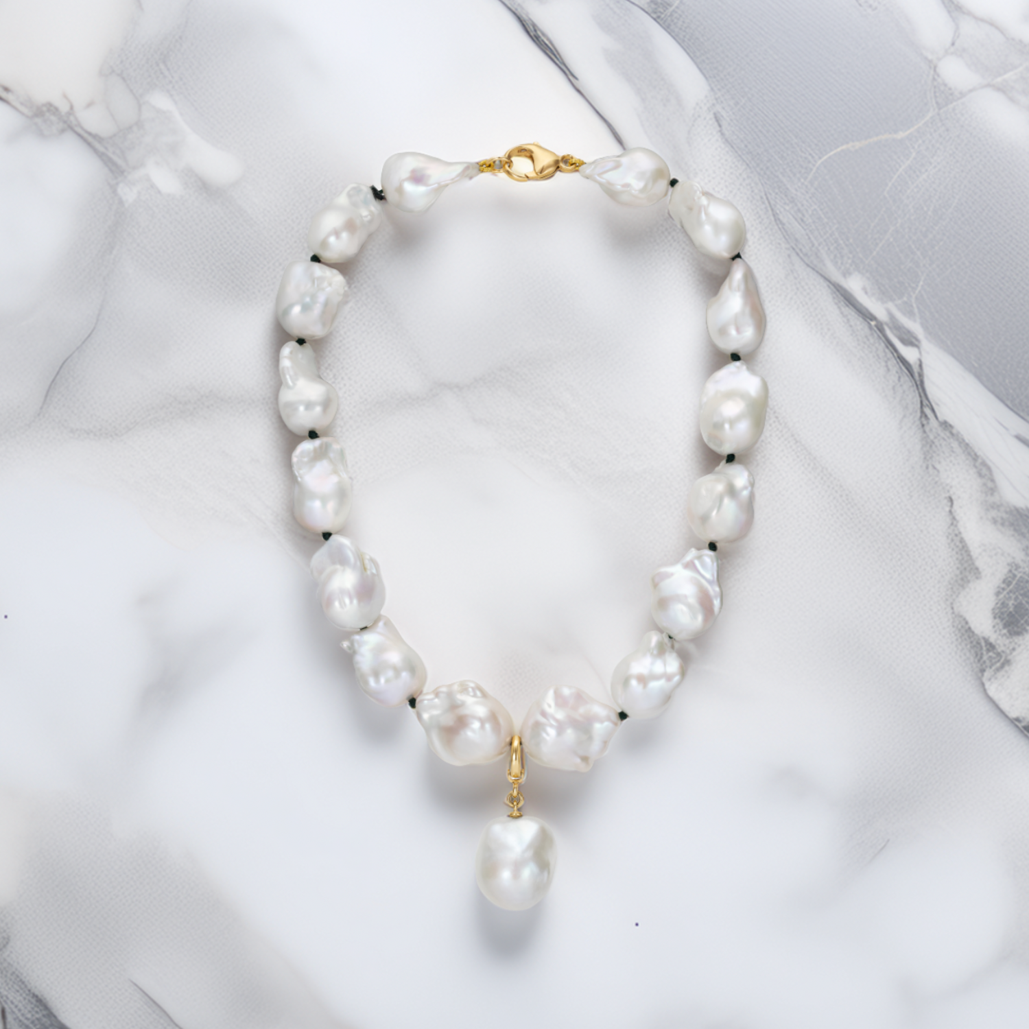 Handcrafted 18K yellow gold Baroque Pearl Necklace featuring unique white baroque freshwater pearls knotted on green thread on marble by Isabella Roux