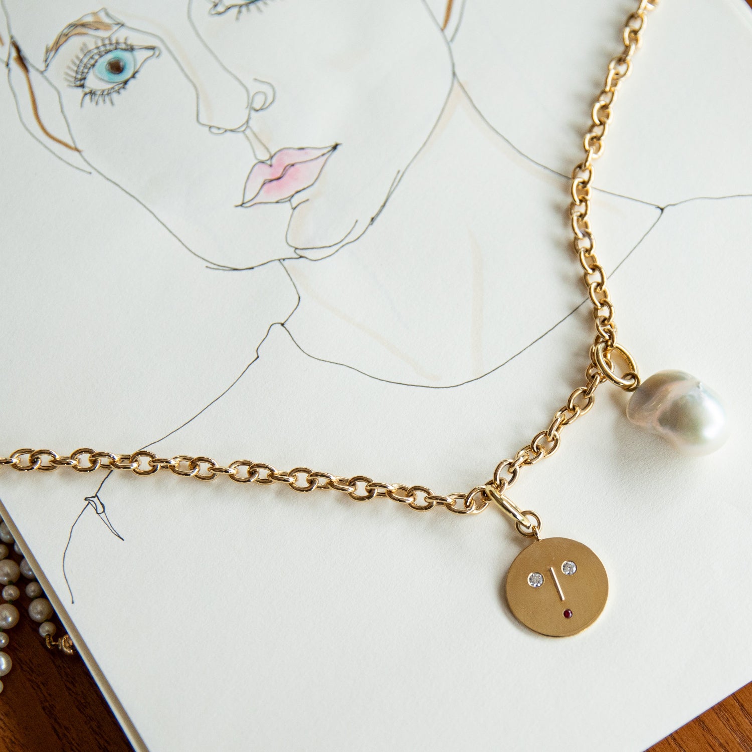 Handcrafted 18K yellow gold Diamond & Ruby Face Charm Pendant featuring a stylized face set with sparkling diamond eyes and ruby mouth by Isabella Roux.