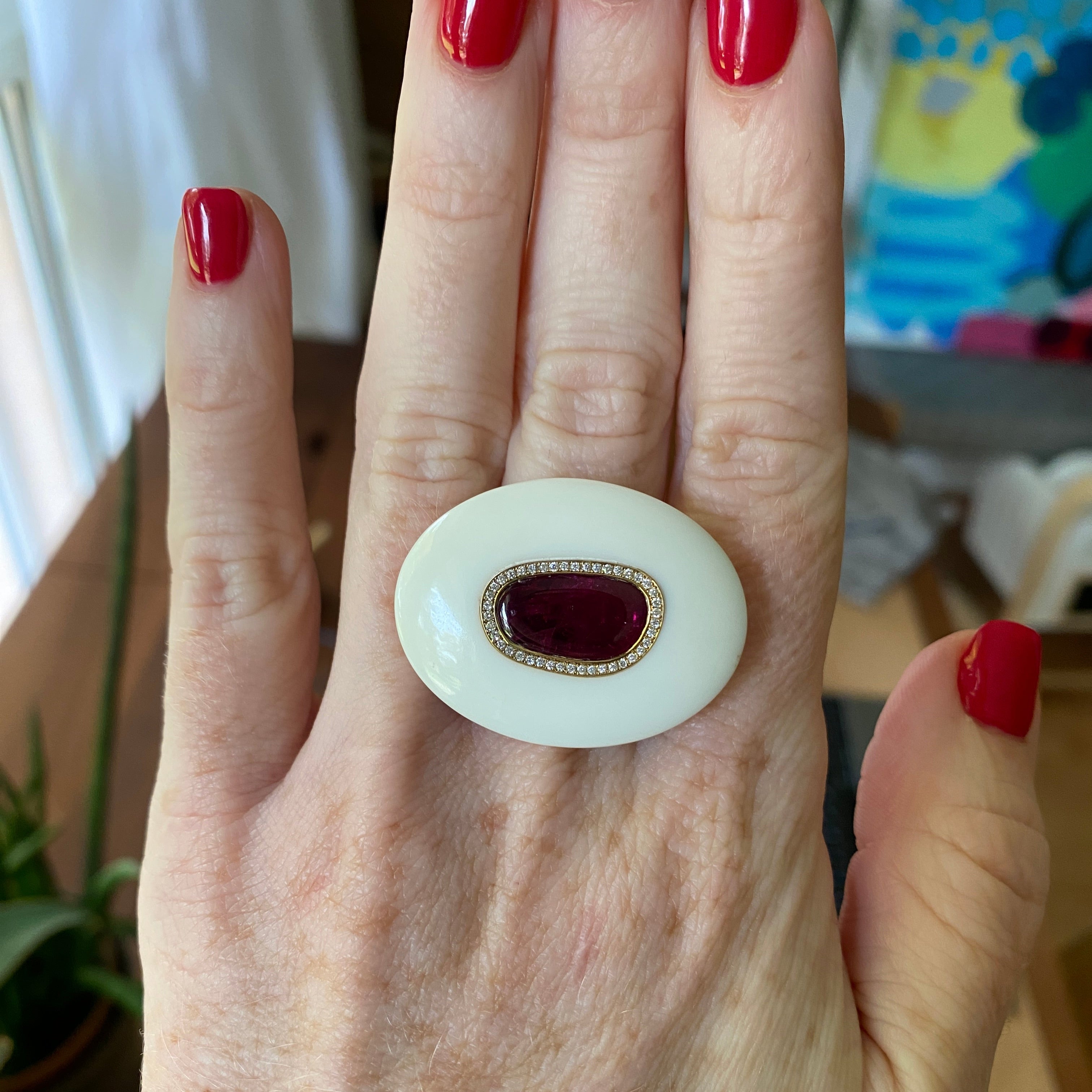 Hand wearing 18K yellow gold Diamond, Ruby & Opal Pebble Ring featuring a 3.21ct ruby slice framed by diamond pavé and set in hand-carved white opal by Isabella Roux.