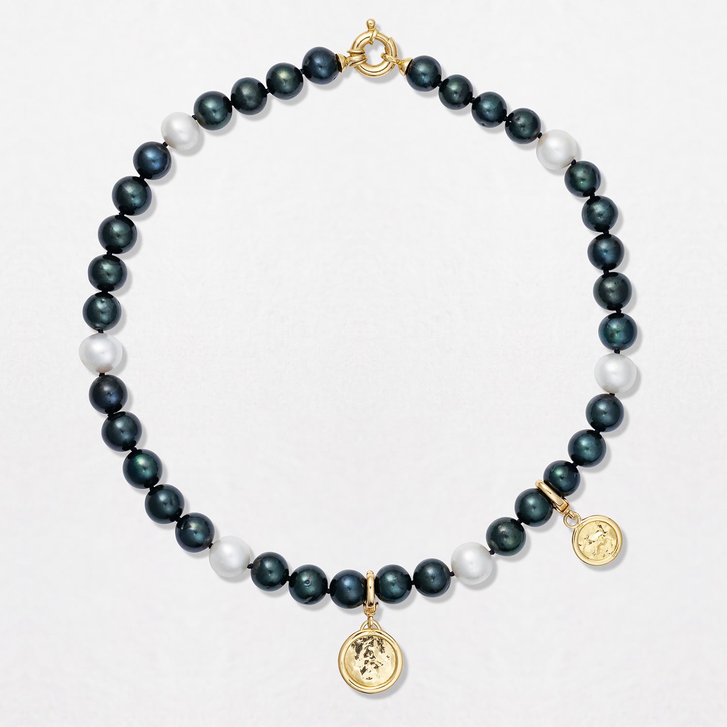 Handcrafted Pebble Black & White Pearl Necklace featuring 9-10mm black and white freshwater pearls knotted on navy thread with an 18K yellow gold clasp and beaten gold disc pendant by Isabella Roux