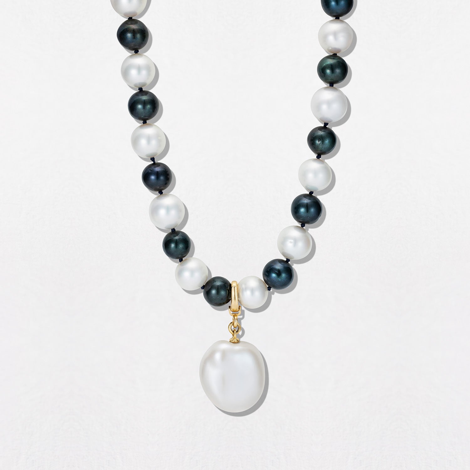 Handcrafted Pebble Monochrome Necklace featuring a set of black and white freshwater pearls knotted on navy thread with 18K yellow gold fittings by Isabella Roux