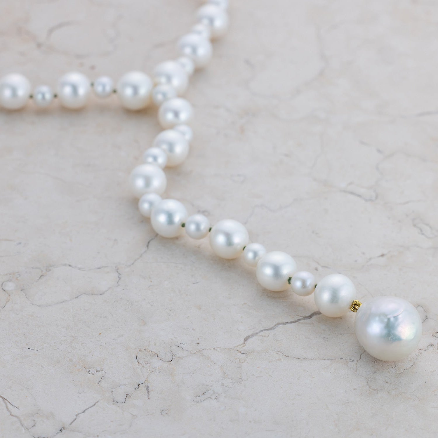 Handcrafted Pebble Pearl Drop Necklace featuring a main pearl and graduating pebble pearls, with 18K yellow gold clasp on green thread, by Isabella Roux