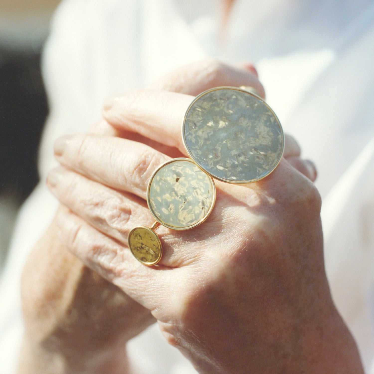 Hand with hand-hammered 18K yellow gold Sun Disc Ring featuring hand-hammered discs on a slim band by Isabella Roux